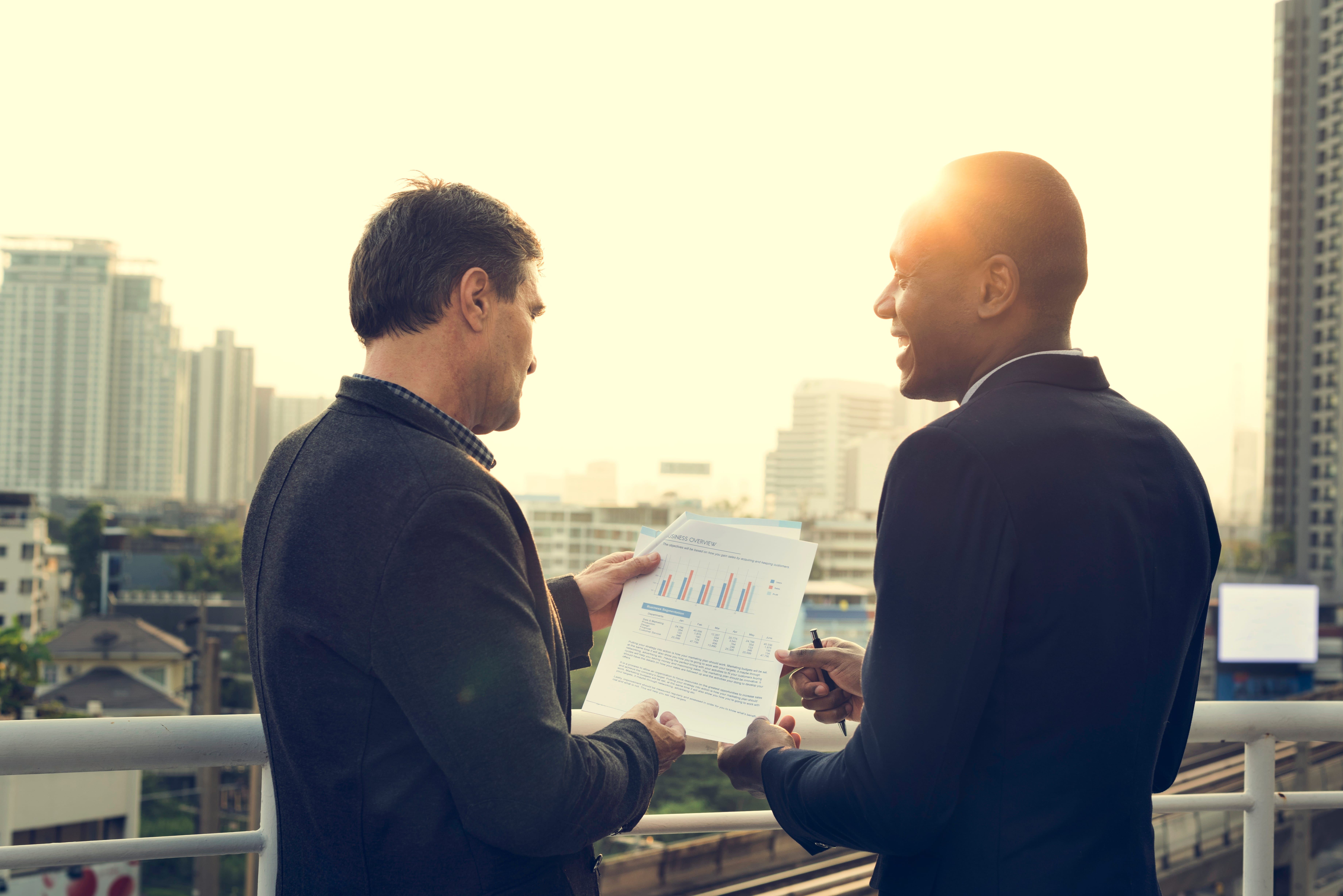 Business professionals reviewing strategic financial reports with city skyline backdrop